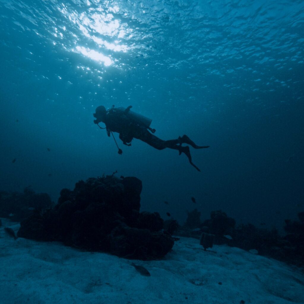 A scuba diver swims above a rock